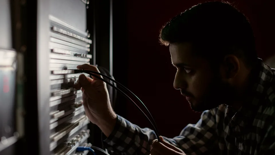 Tecnico al lavoro su un telaio di permutazione, in controluce